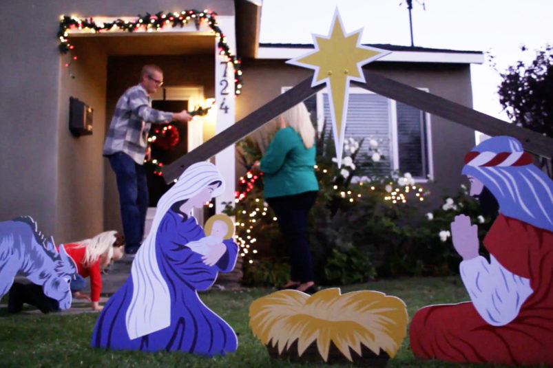 Family decorating outside of house for Christmas with nativity scene