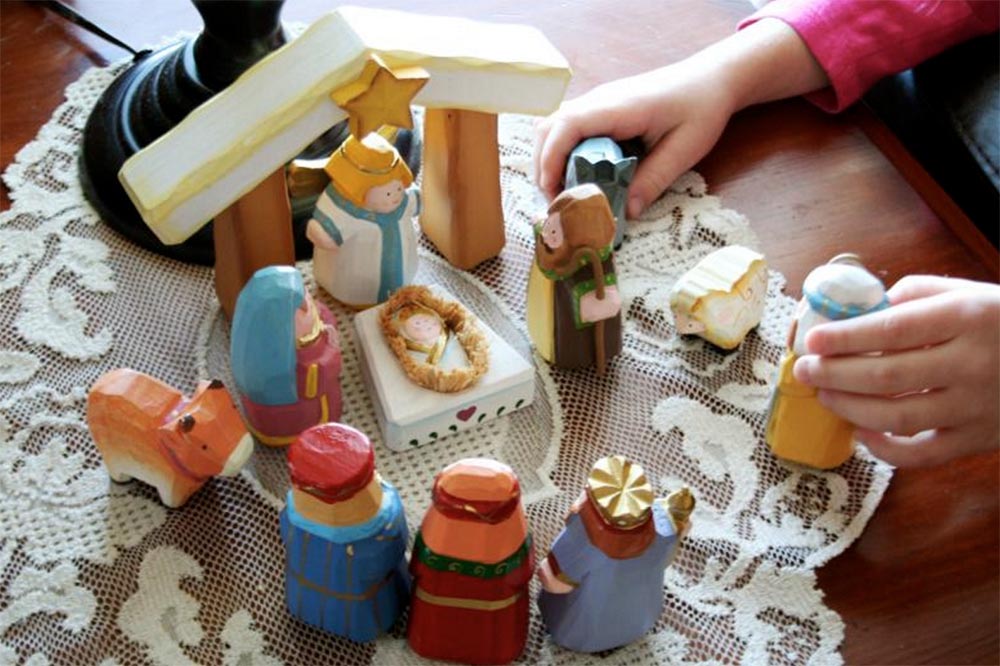 Child playing with small wooden nativity set
